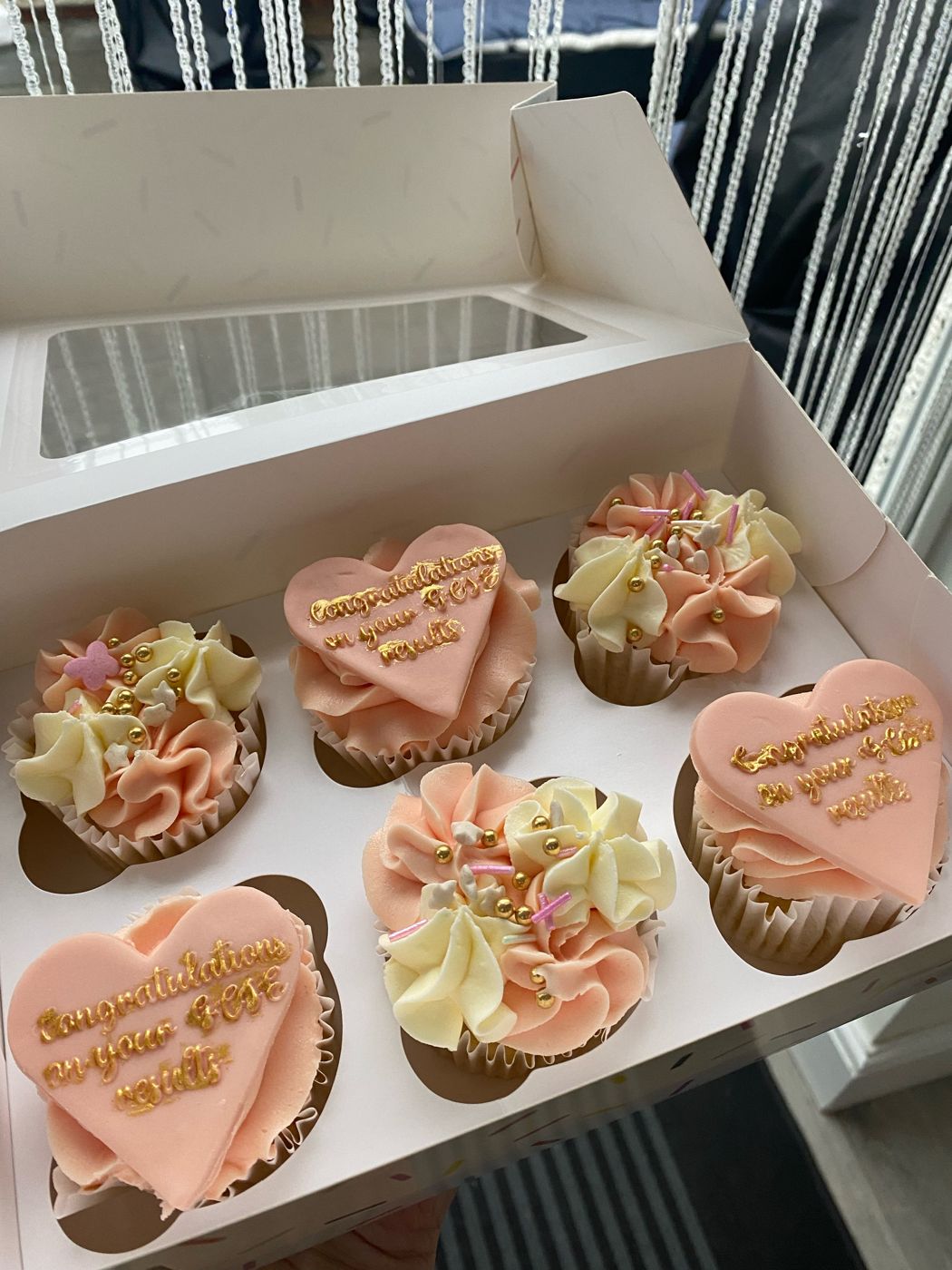 A box of mini heart cupcakes with gold piped congratulations